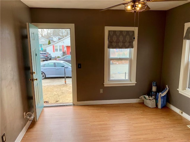 doorway with ceiling fan, light hardwood / wood-style floors, and a healthy amount of sunlight