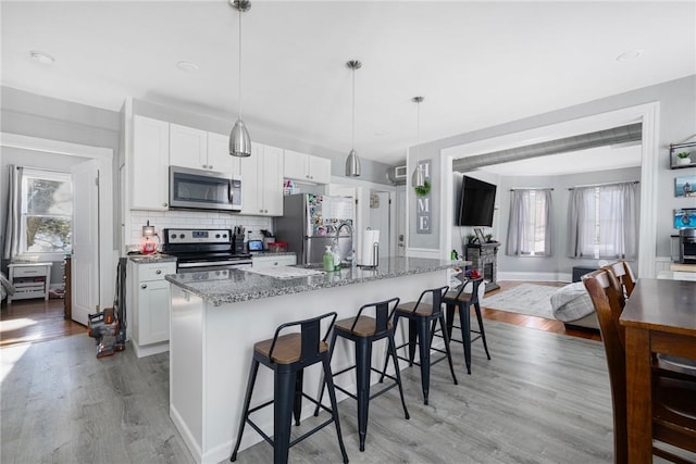 kitchen with white cabinetry, light wood-type flooring, a kitchen island with sink, and appliances with stainless steel finishes