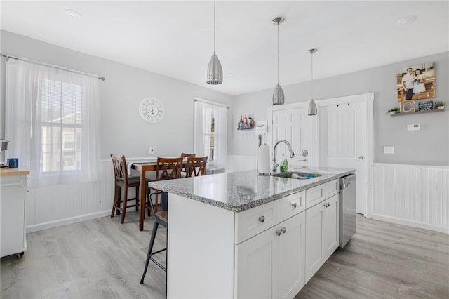 kitchen with decorative light fixtures, sink, white cabinets, a kitchen island with sink, and stainless steel dishwasher