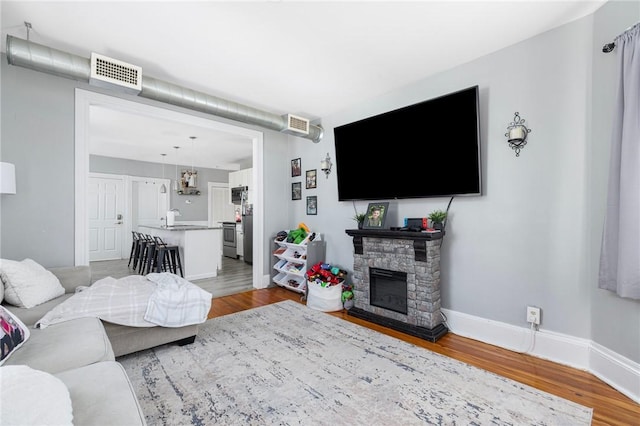 living room featuring a stone fireplace, sink, and light wood-type flooring