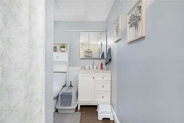 bathroom featuring vanity, tile patterned flooring, toilet, and a drop ceiling