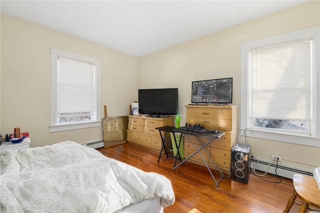 bedroom featuring hardwood / wood-style flooring and a baseboard heating unit