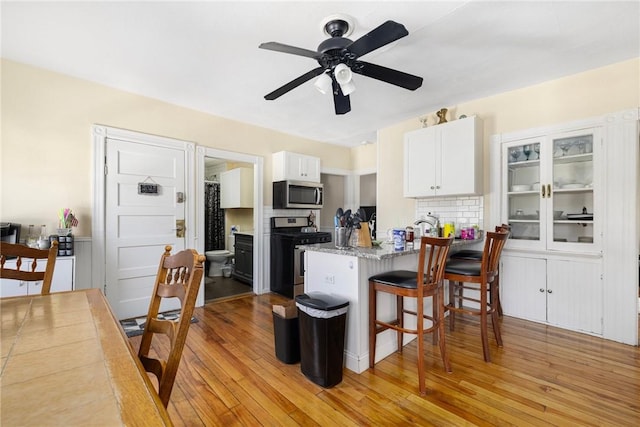 kitchen featuring appliances with stainless steel finishes, kitchen peninsula, light hardwood / wood-style floors, and white cabinets