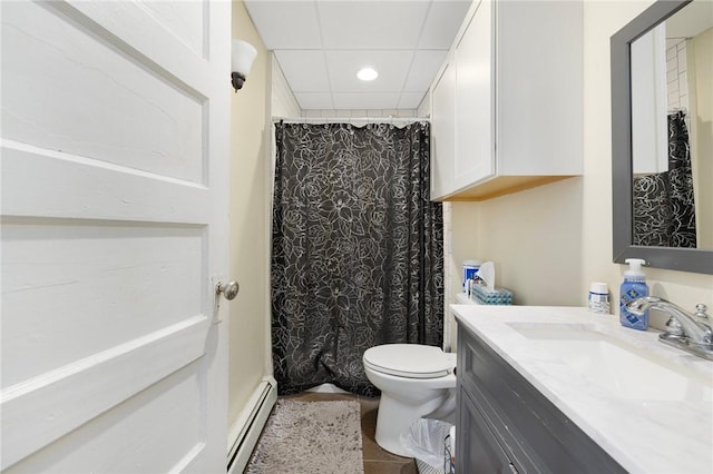 bathroom featuring tile patterned flooring, a baseboard heating unit, vanity, a drop ceiling, and toilet