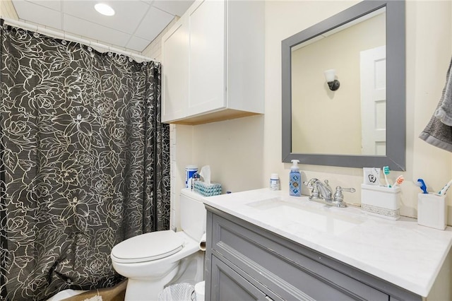 bathroom featuring vanity, toilet, and a drop ceiling