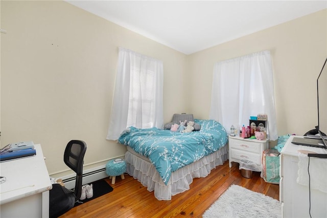 bedroom with a baseboard heating unit and light hardwood / wood-style flooring