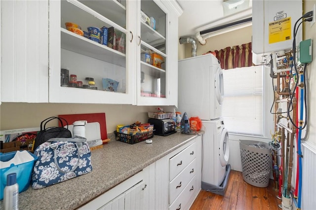 kitchen with white cabinetry, stacked washing maching and dryer, dark hardwood / wood-style flooring, and water heater