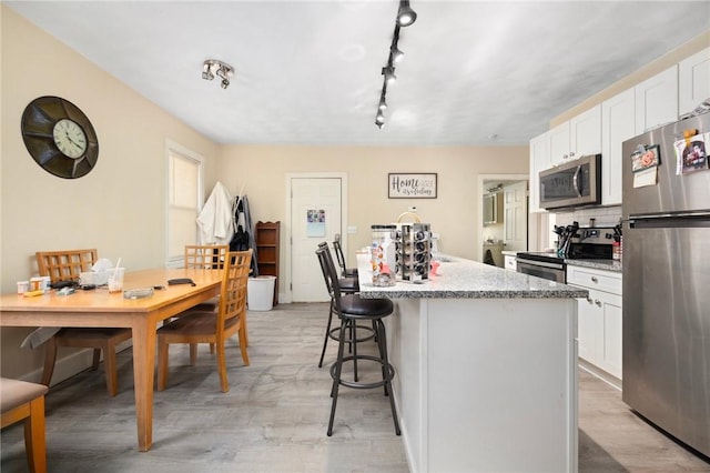 kitchen featuring white cabinetry, light hardwood / wood-style flooring, stainless steel appliances, and a center island