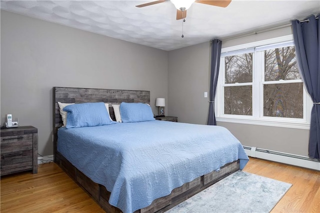 bedroom featuring baseboard heating, ceiling fan, and wood-type flooring