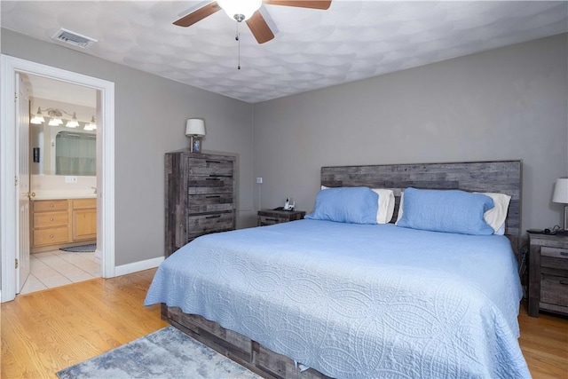 bedroom with light hardwood / wood-style floors, ceiling fan, and ensuite bath