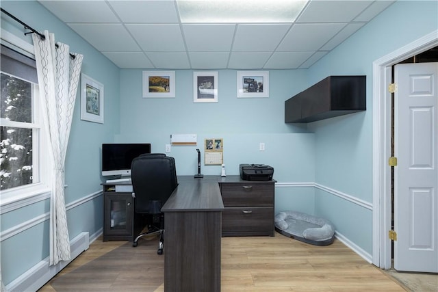 home office with light hardwood / wood-style floors and a drop ceiling