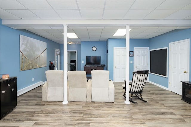 living room with a drop ceiling, hardwood / wood-style flooring, a baseboard radiator, and ornate columns