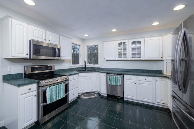 kitchen featuring dark tile patterned floors, white cabinetry, appliances with stainless steel finishes, and sink