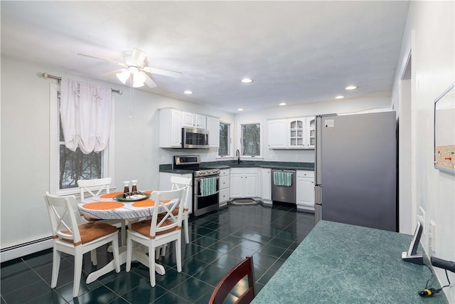 kitchen with white cabinetry, sink, dark tile patterned floors, a baseboard heating unit, and stainless steel appliances