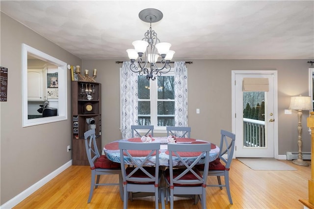 dining room with light hardwood / wood-style floors, a chandelier, and baseboard heating