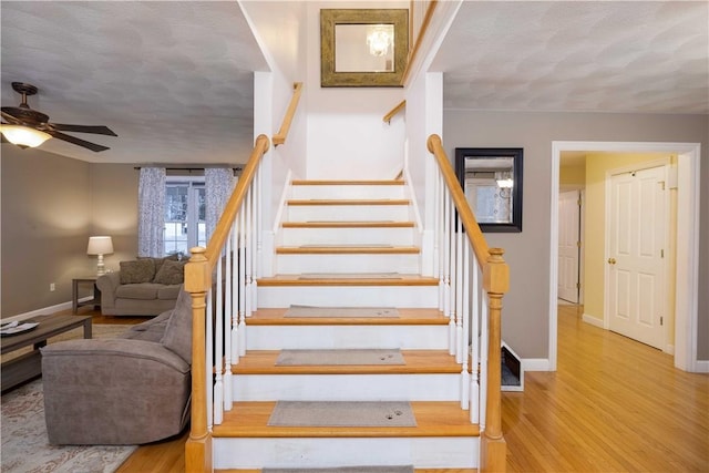 stairway featuring hardwood / wood-style flooring, a textured ceiling, and ceiling fan