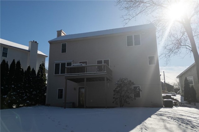 snow covered back of property with a balcony