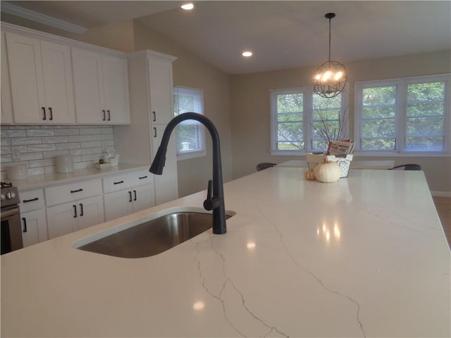 kitchen with light stone counters, sink, and white cabinetry