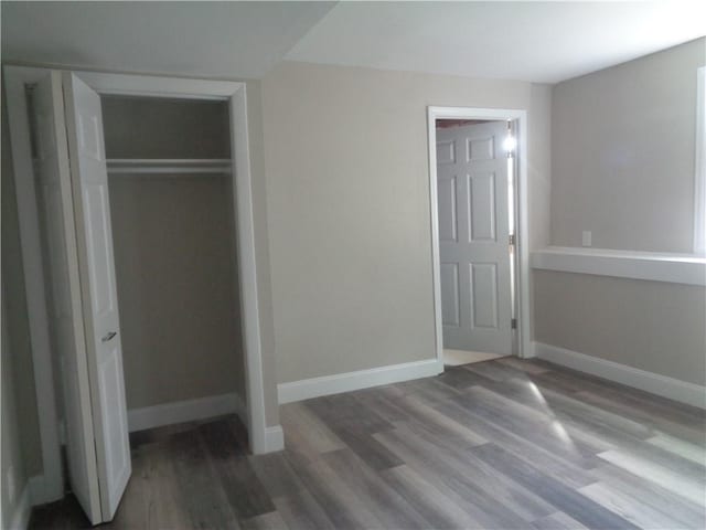 unfurnished bedroom with dark wood-type flooring and a closet