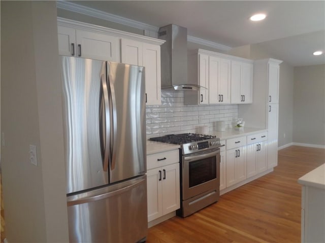 kitchen with wall chimney exhaust hood, stainless steel appliances, and white cabinets