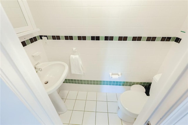 bathroom with tile patterned flooring, toilet, and tile walls