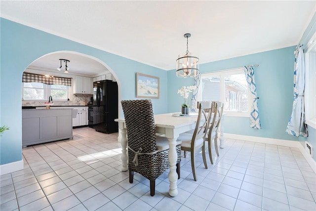 tiled dining area featuring crown molding and a chandelier