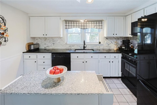 kitchen featuring sink, black appliances, dark stone counters, decorative backsplash, and white cabinets