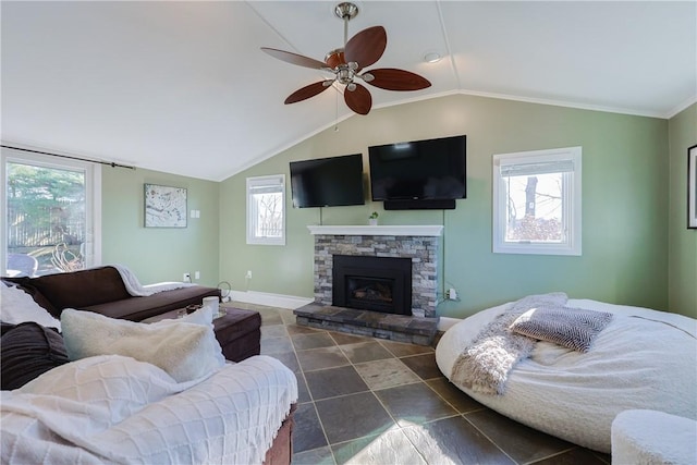 living room featuring vaulted ceiling, a stone fireplace, and ceiling fan