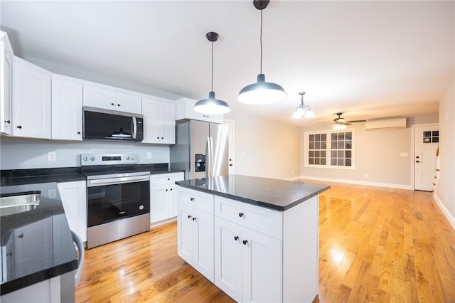 kitchen with stainless steel appliances, white cabinetry, hanging light fixtures, and a wall mounted AC