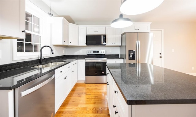 kitchen featuring stainless steel appliances, hanging light fixtures, sink, and white cabinets