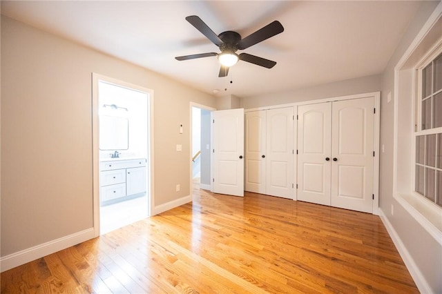 unfurnished bedroom featuring ensuite bathroom, a closet, ceiling fan, and light hardwood / wood-style flooring