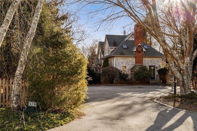 view of side of home featuring stone siding and a chimney