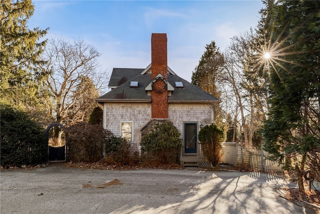 view of front of home featuring a gate, fence, and a chimney