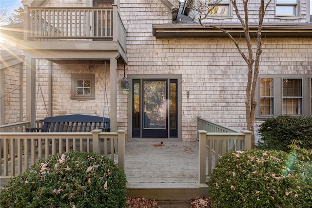 view of exterior entry with a wooden deck and a balcony