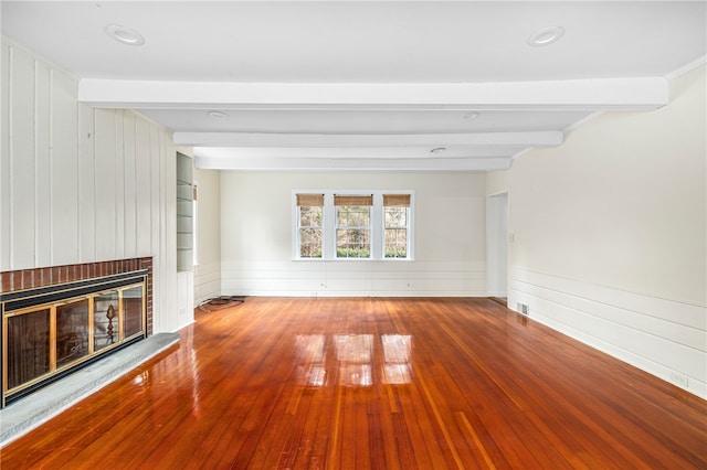 unfurnished living room with beamed ceiling, wood-type flooring, and a brick fireplace