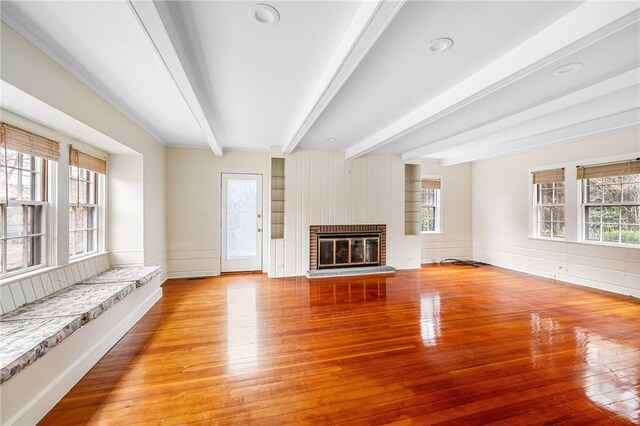 unfurnished living room with light wood-type flooring, a fireplace, and beam ceiling