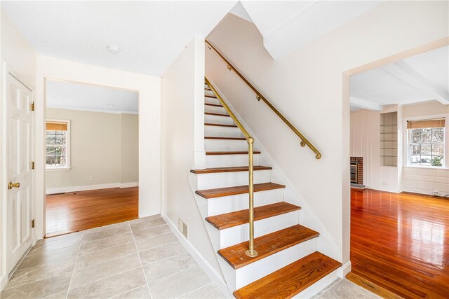 stairs with visible vents, plenty of natural light, a fireplace, and wood finished floors