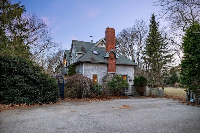 view of property exterior featuring aphalt driveway and a chimney