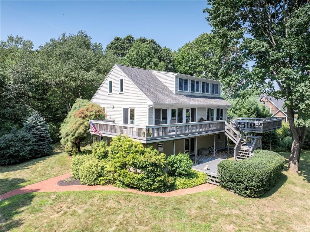 rear view of property featuring a deck and a lawn