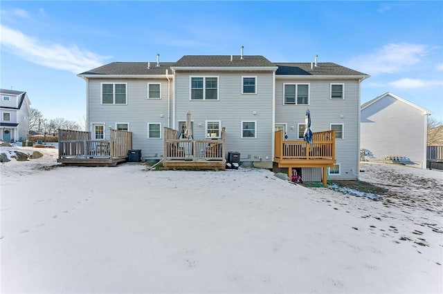 snow covered rear of property featuring a wooden deck and central AC