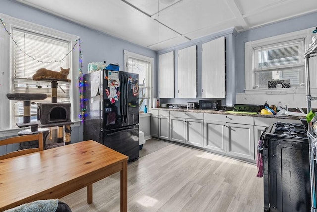 kitchen featuring gas range, black fridge, and light hardwood / wood-style flooring