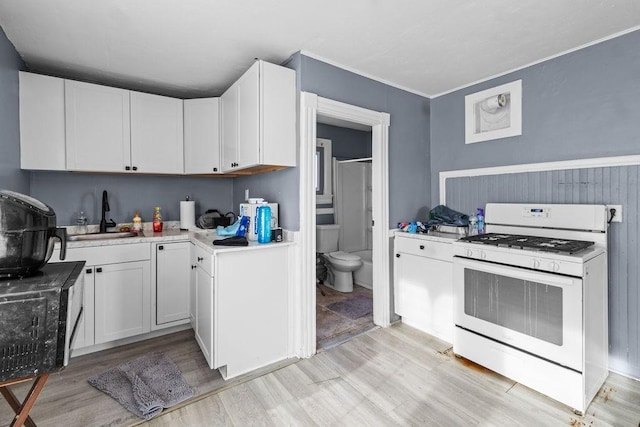 kitchen featuring white cabinetry, white gas range, sink, and light hardwood / wood-style floors