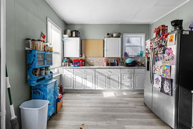 kitchen featuring white cabinetry, stainless steel refrigerator with ice dispenser, tasteful backsplash, and light hardwood / wood-style floors