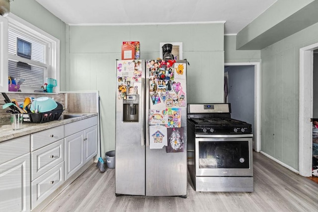 kitchen with white cabinetry, light stone counters, light hardwood / wood-style flooring, and stainless steel appliances