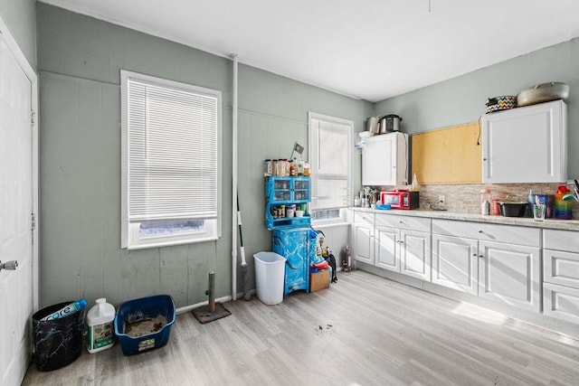 kitchen with tasteful backsplash, white cabinetry, and light hardwood / wood-style flooring