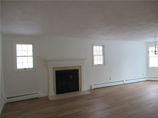 unfurnished living room featuring a baseboard radiator, wood-type flooring, and plenty of natural light