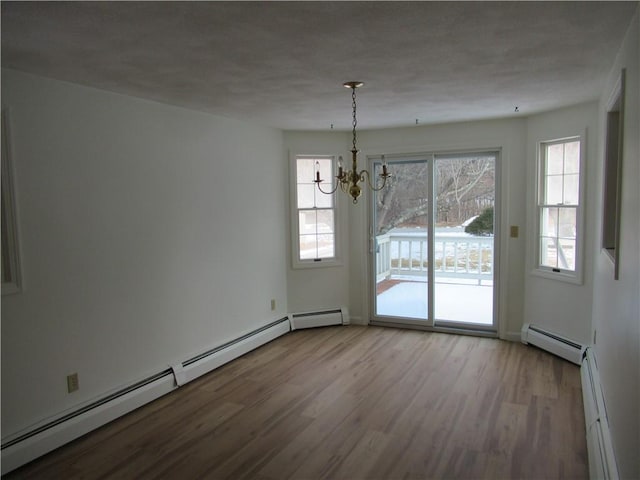 unfurnished dining area with plenty of natural light, a baseboard heating unit, and light hardwood / wood-style floors