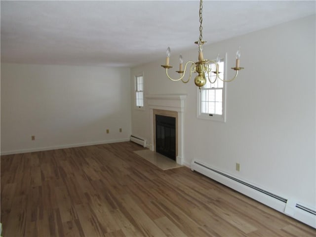 unfurnished living room with hardwood / wood-style floors, a notable chandelier, and baseboard heating