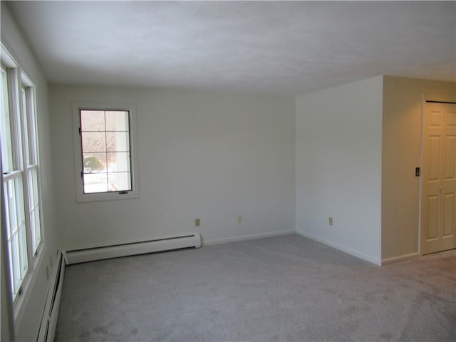 carpeted spare room with a baseboard heating unit