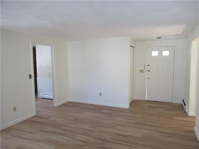 foyer entrance with a baseboard radiator and light wood-type flooring